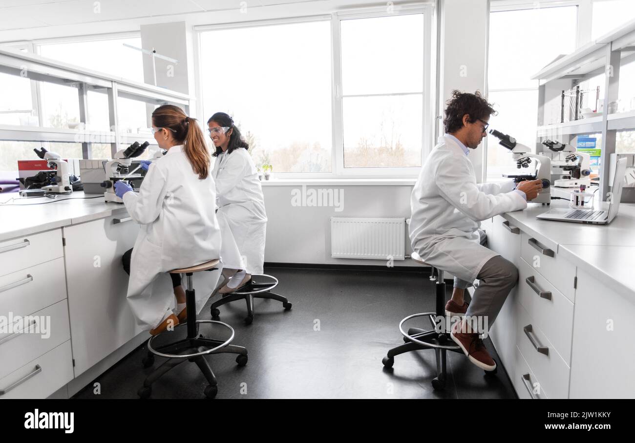 scientists with microscopes working in laboratory Stock Photo - Alamy
