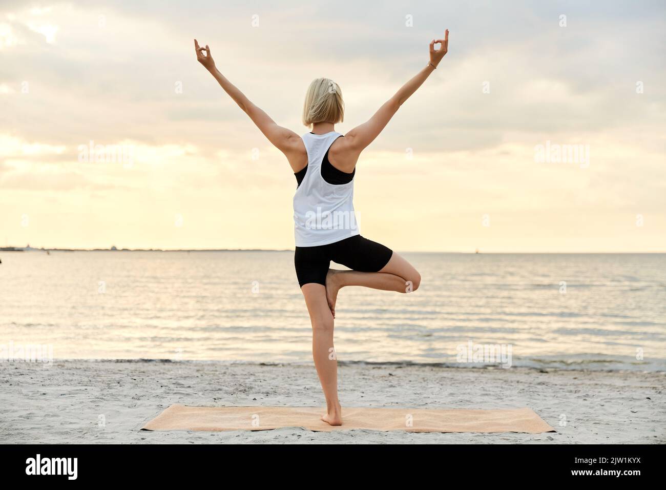 Woman doing yoga tree pose on the beach hi-res stock photography and ...