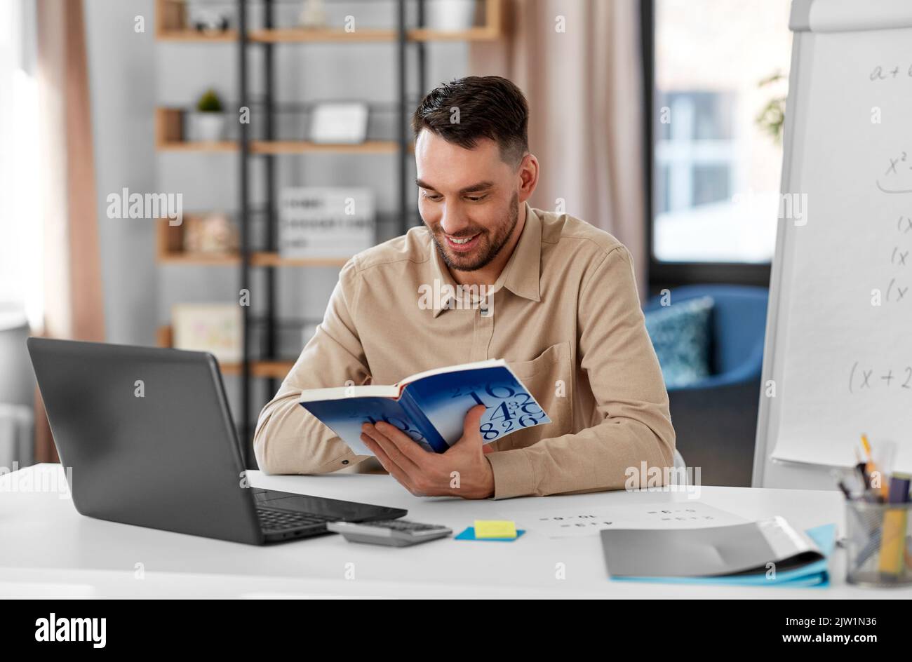 math teacher with laptop and book at home office Stock Photo