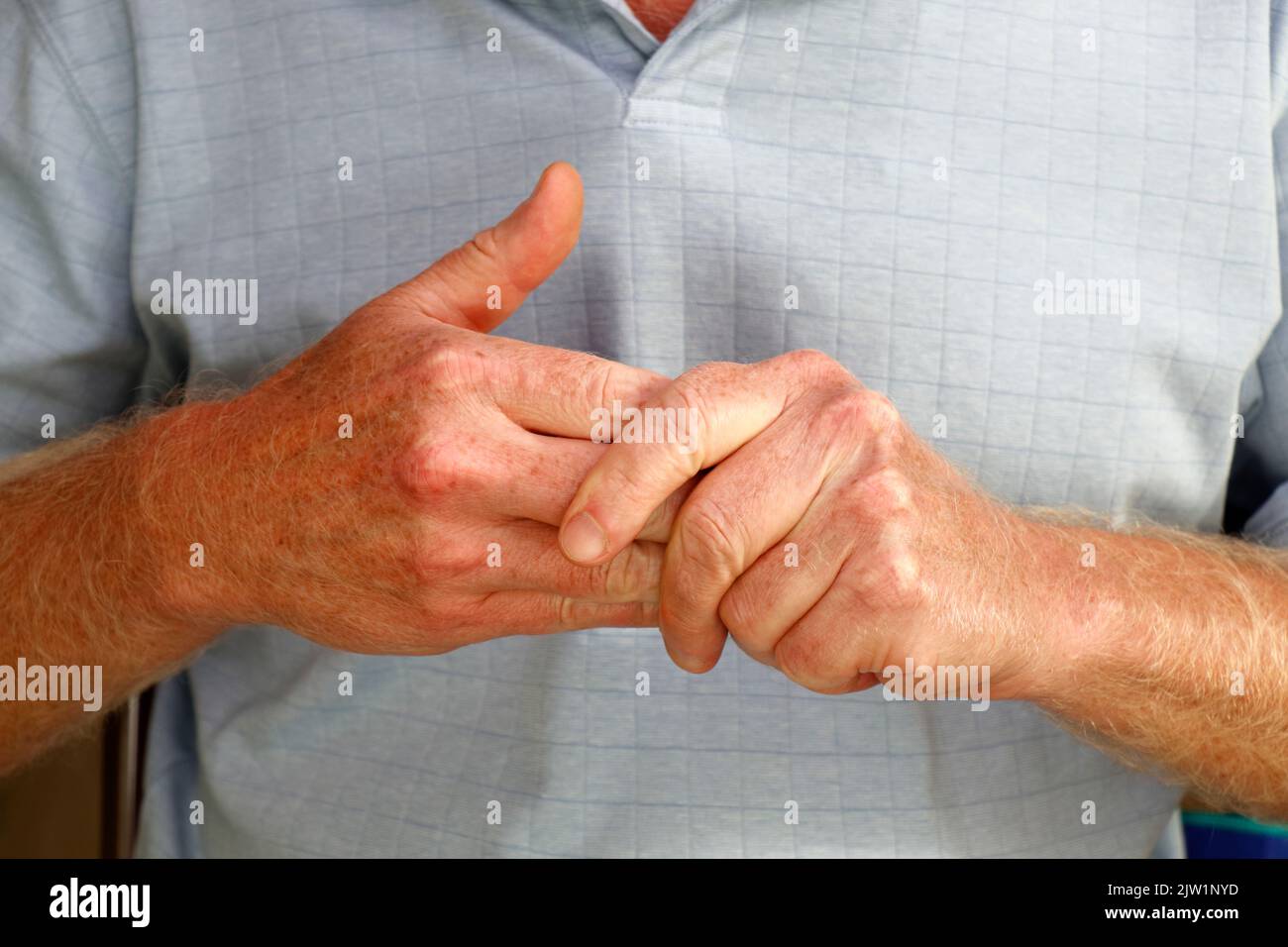 Close-up of mature caucasian males left hand massaging the fingers of his right hand to ease any pain and soreness in muscles and joints. Stock Photo