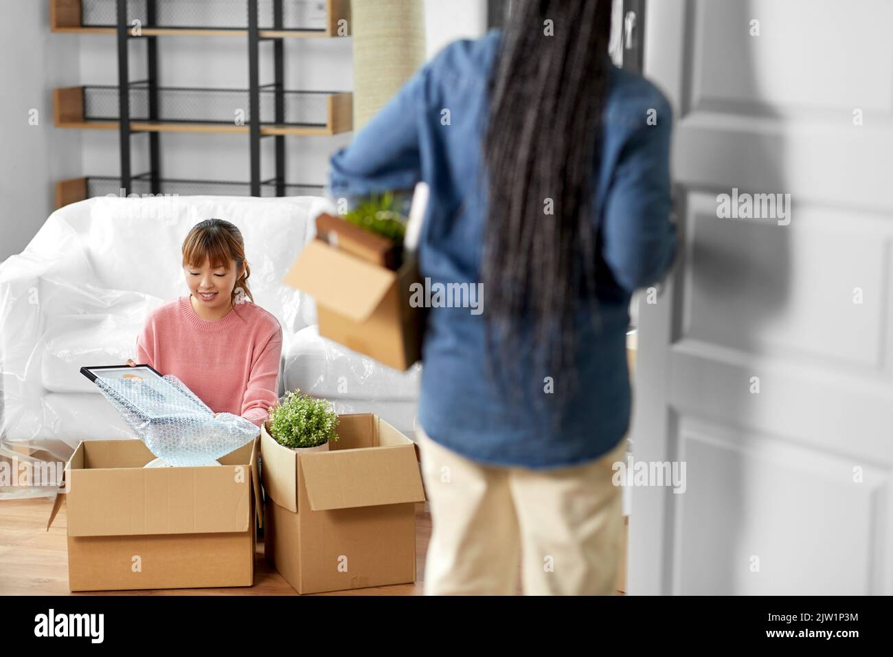 Two women friends entering room hi-res stock photography and images - Alamy