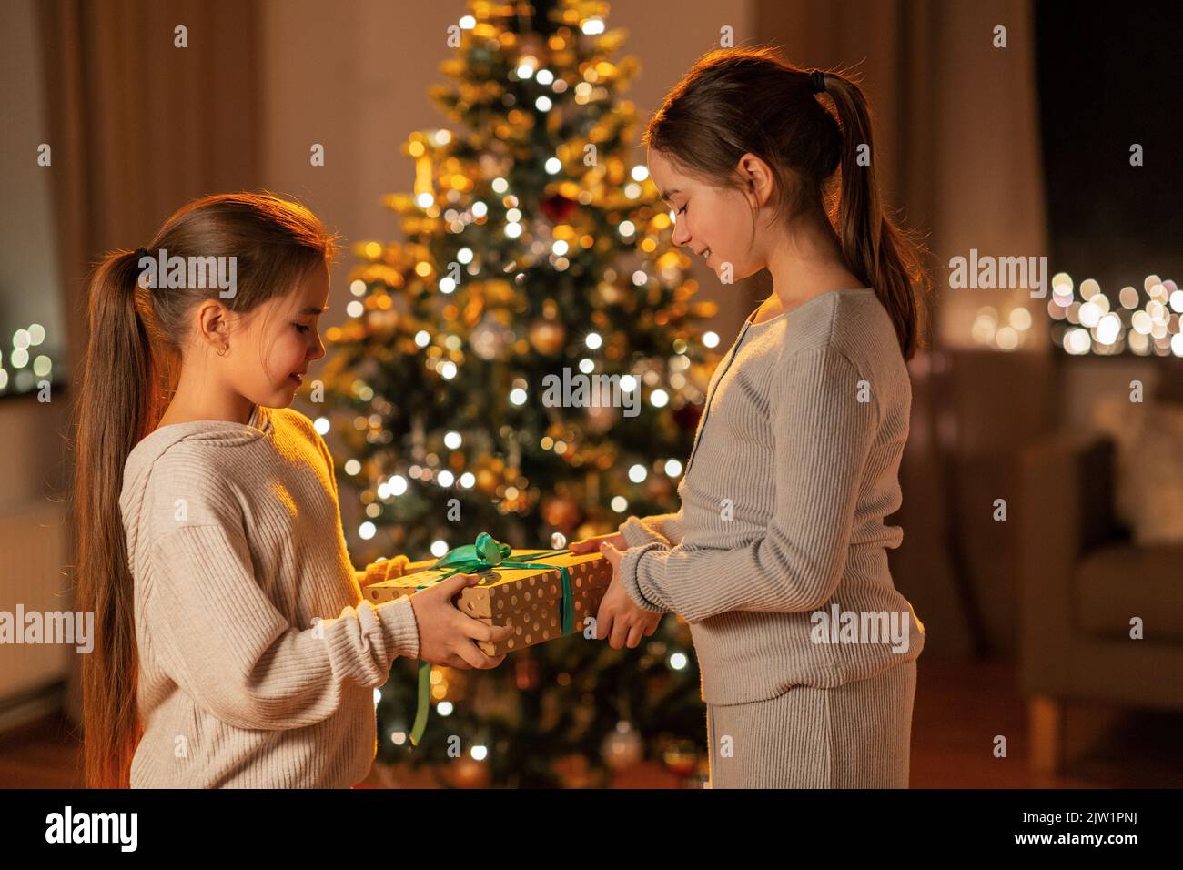 happy girls holding christmas gift at home Stock Photo - Alamy