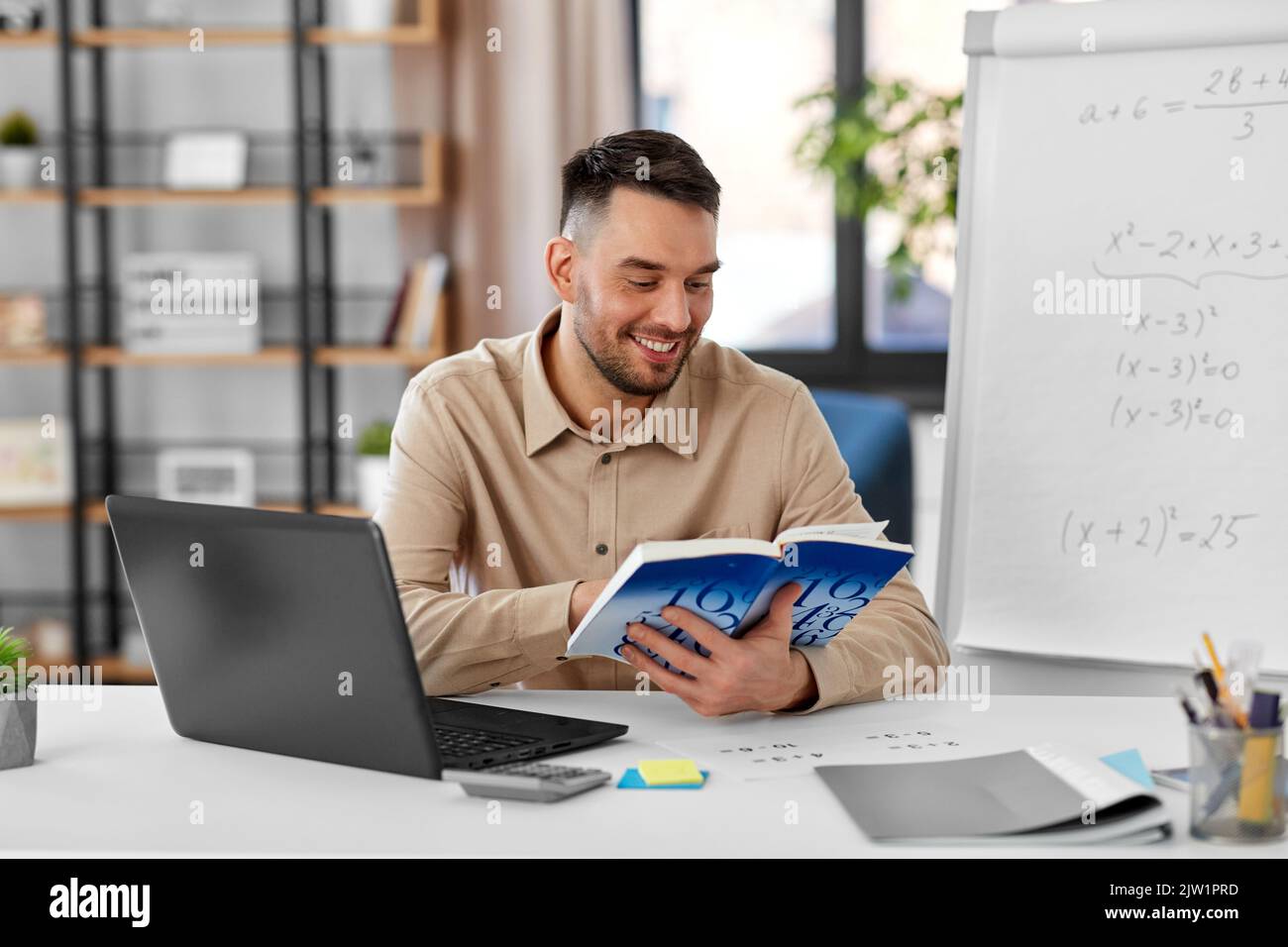 math teacher with laptop and book at home office Stock Photo