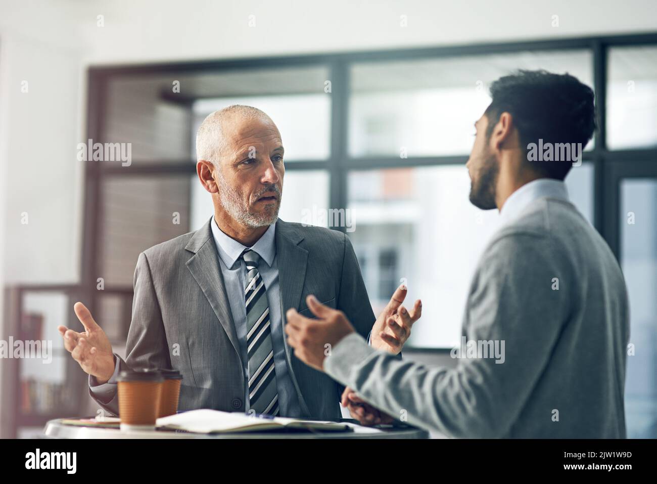 Whats the hold up. two businessmen talking in their office Stock Photo ...