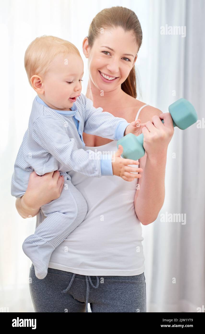 Ill take that for now. a young woman working out while spending time with her baby boy. Stock Photo