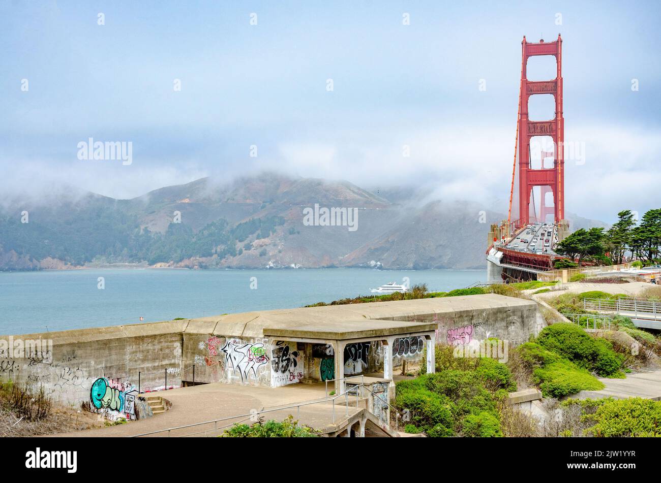 Old World War 2 concrete bunkers with graffiti in the foreground with The Golden Gate Bridge in the background in San Francisco, California, USA Stock Photo