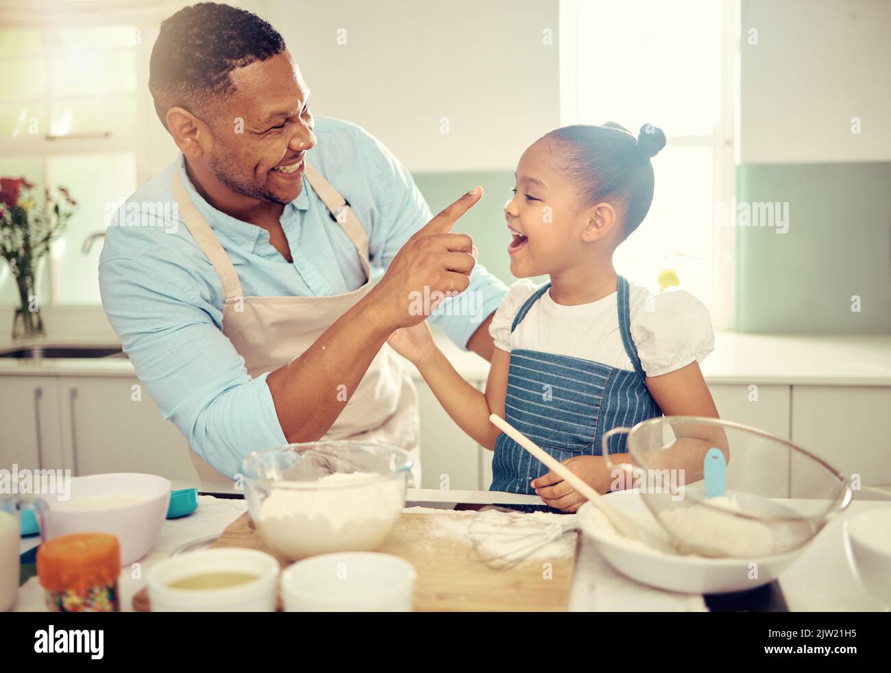 Baking dad, funny daughter and flour nose messy joke from happy learning, laughing child development and bonding in kitchen. Parent, kids and family Stock Photo