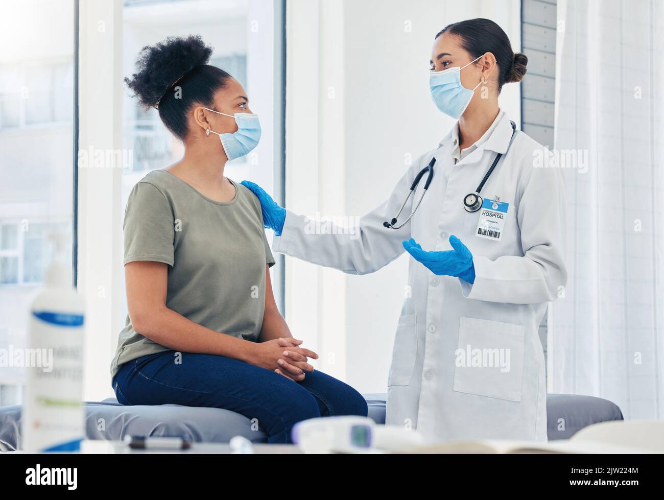 Medical nurse consulting a patient for covid before vaccine while wearing a face mask during pandemic. Healthcare worker with stethoscope discussing Stock Photo