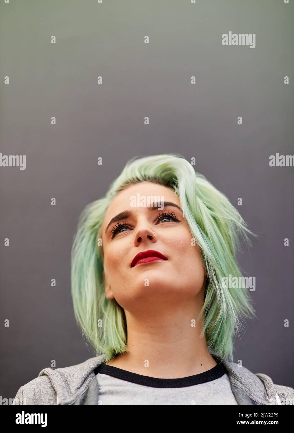 Colorful hair has character. a trendy young woman with mint green hair posing against a gray background. Stock Photo