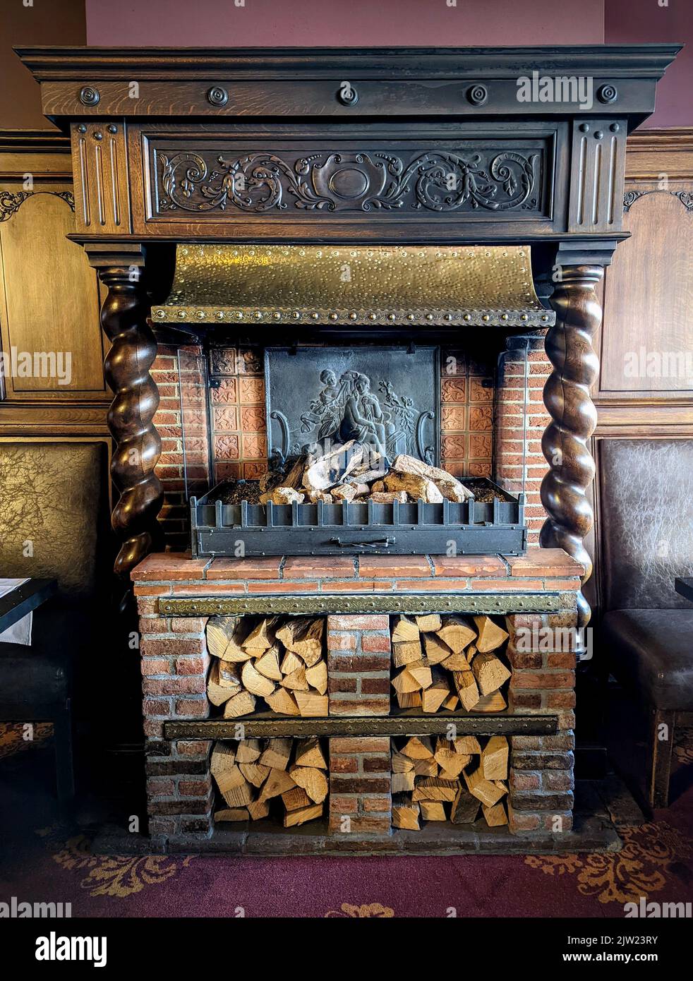 A vertical shot of an old fireplace with firewood in the shelf Stock Photo
