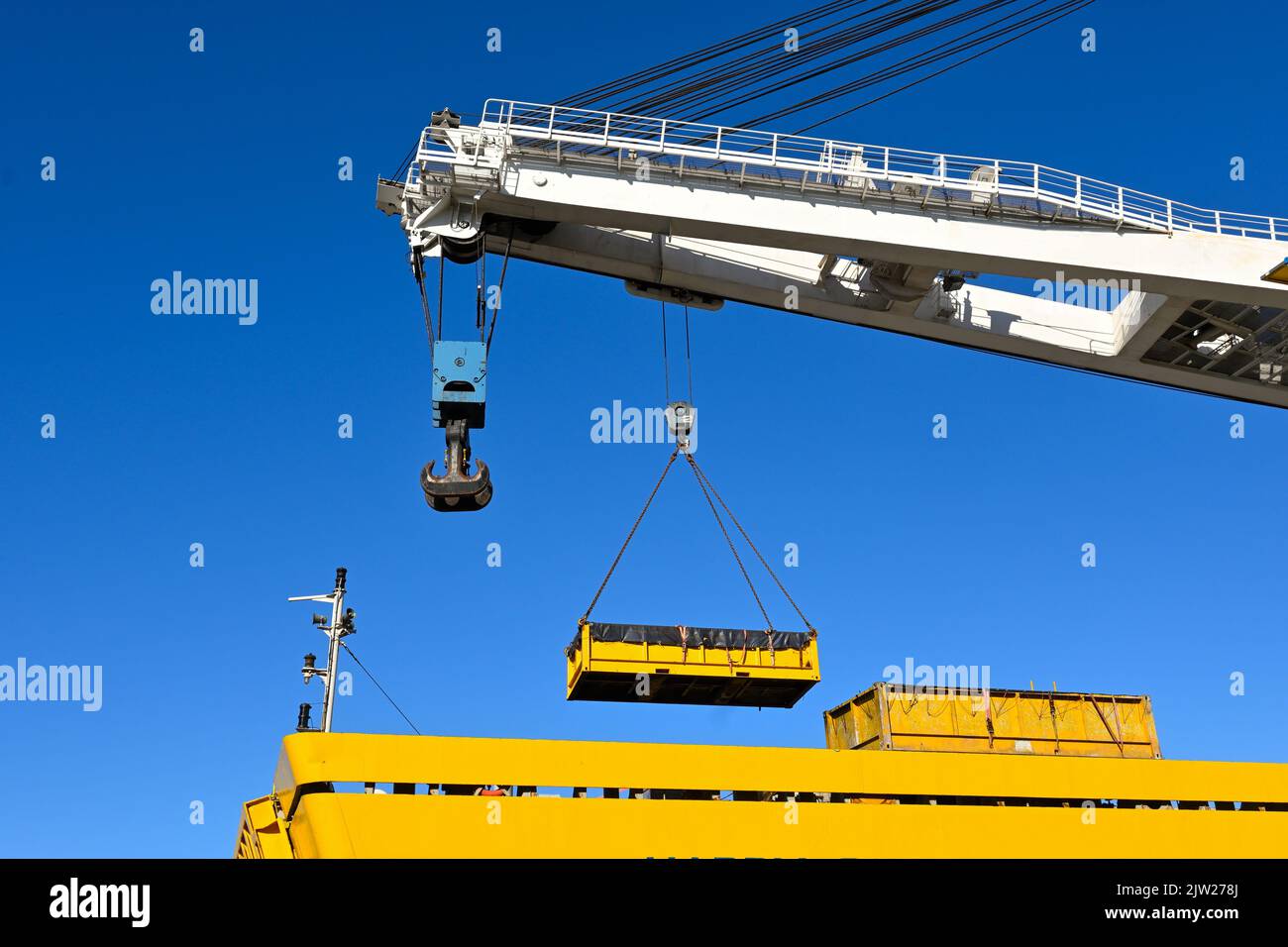 Yellow outdoor crane used in ship industry, electric overhead traveling crane above the vessel Stock Photo