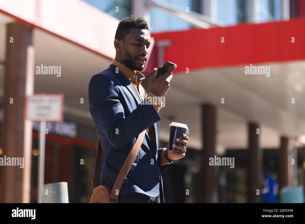 African american man walking talking using smartphone and drinking coffee Stock Photo