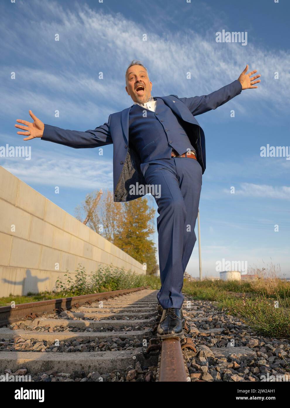 Drunk man in suit balancing over railway tracks at the harbour ...