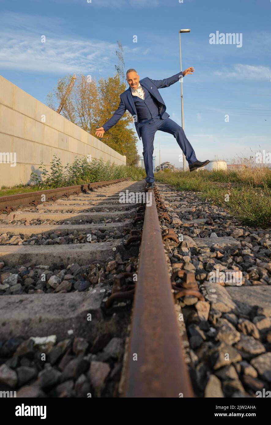 Drunk man in suit balancing over railway tracks at the harbour ...