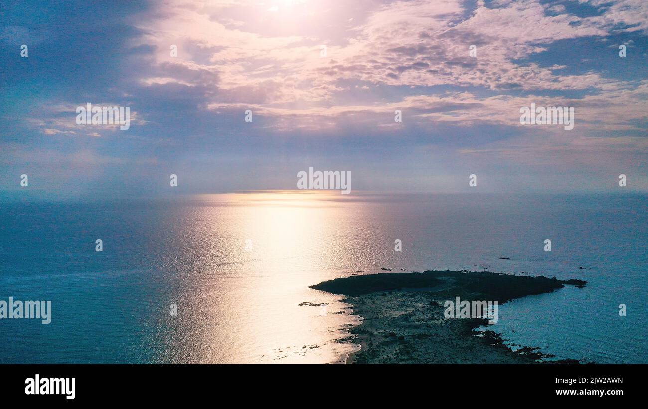 Backlight shot, cloudy blue sky, sunbeam on lagoon, rocky headland, Elafonissi beach, Southwest Crete, Crete Island, Greek Islands, Greece Stock Photo