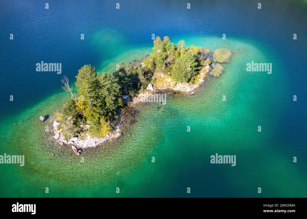 Aerial view of a small island with trees in the blue-green water of the ...