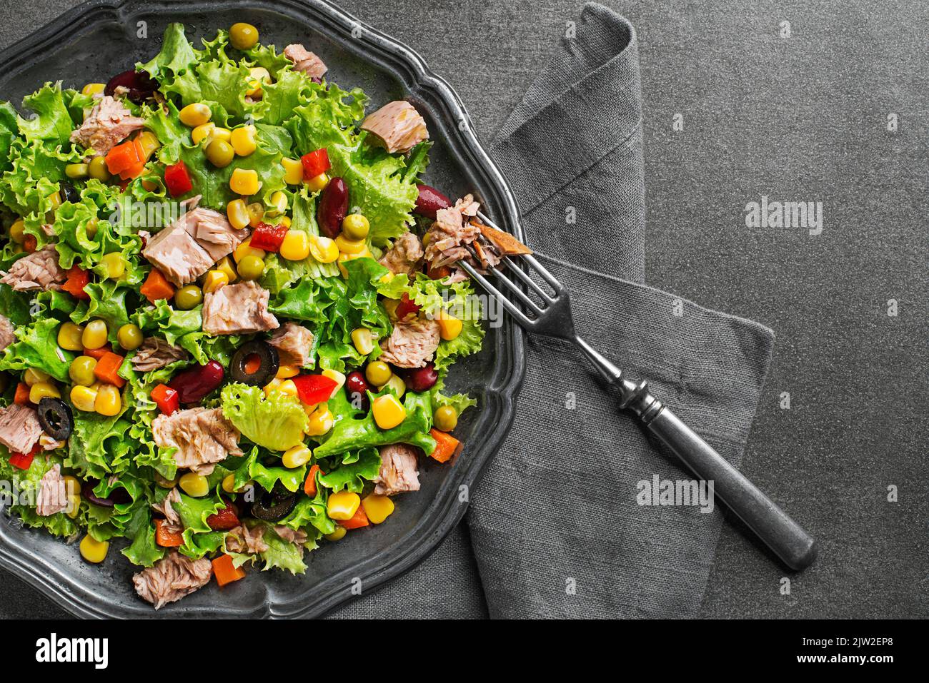 Healthy Green salad with tuna and vegetable on grey background close up. Mexican corn salad. Stock Photo