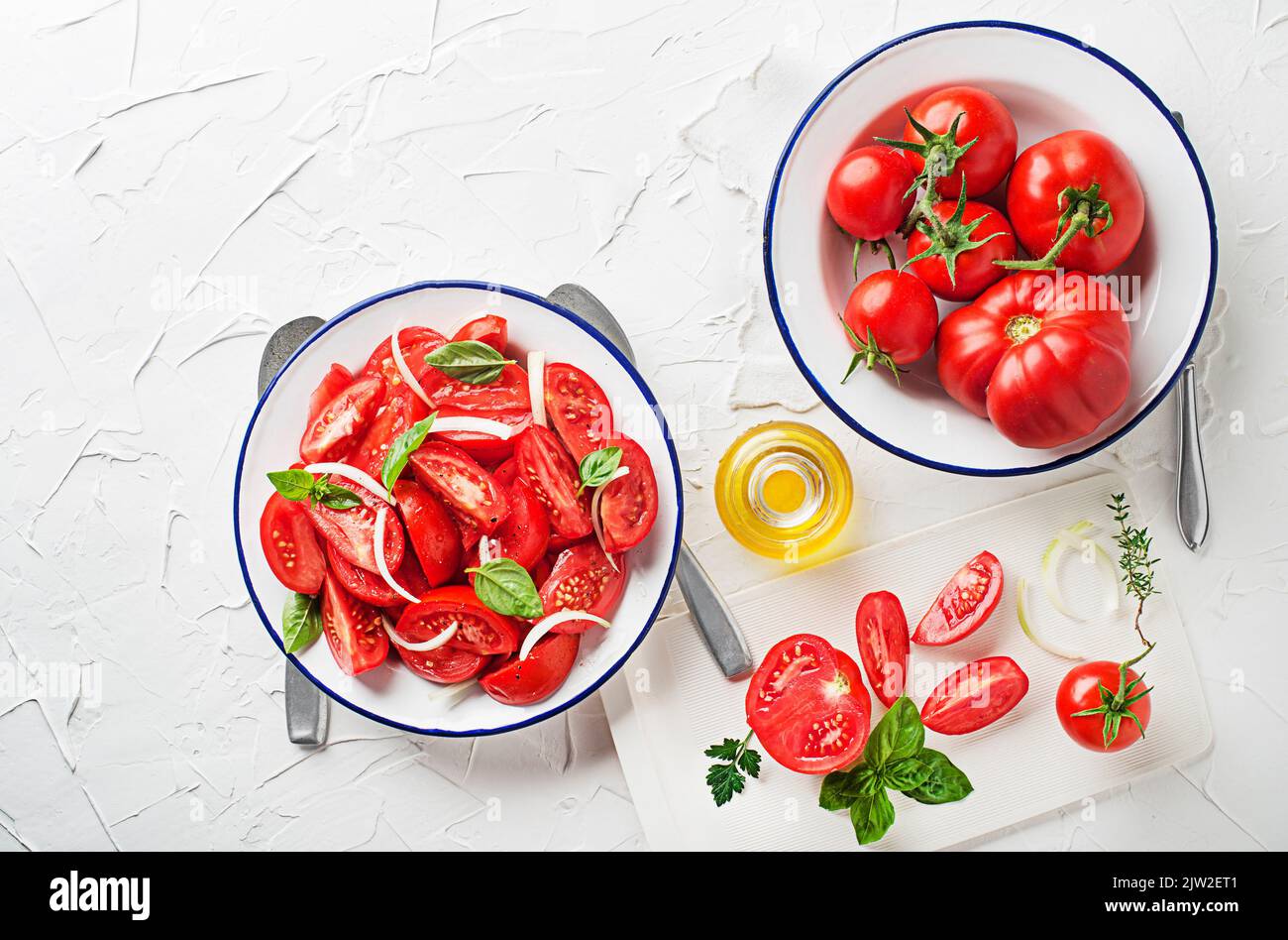 Fresh tomato salad with onion and basil on white table background ...