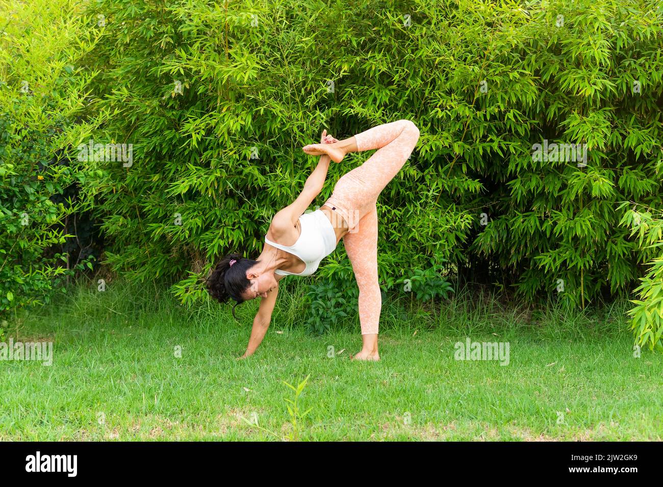 Fit woman doing ardha chandra chapasana yoga pose Stock Photo by