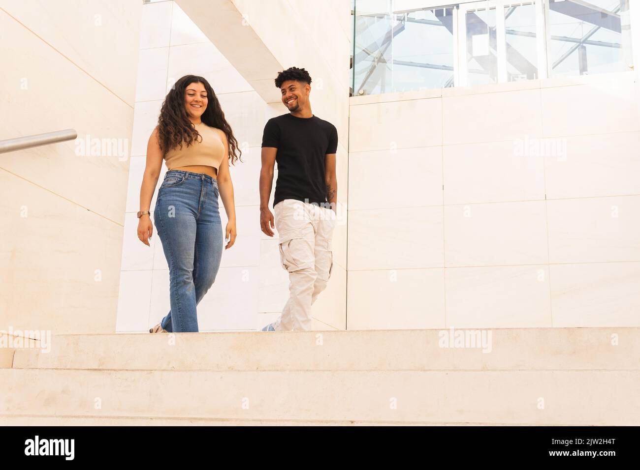 Smiling young man looking at girlfriend while walking in corridor Stock Photo