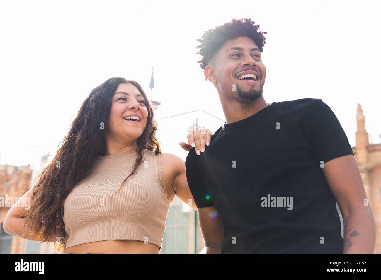 From below cheerful young couple laughing while standing in city Stock Photo