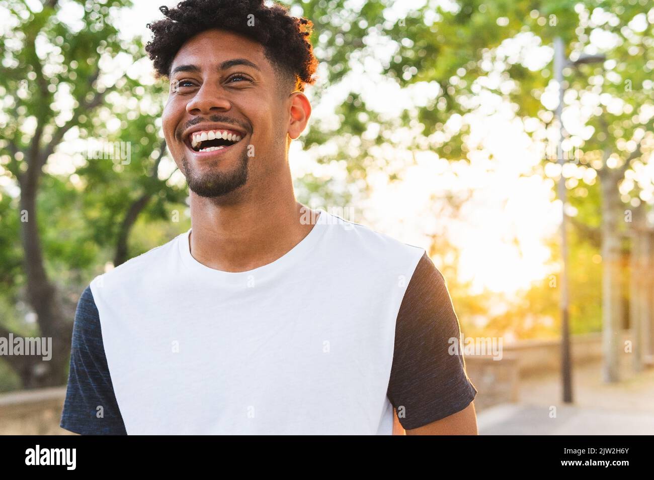 Cheerful young man looking away while standing at park Stock Photo