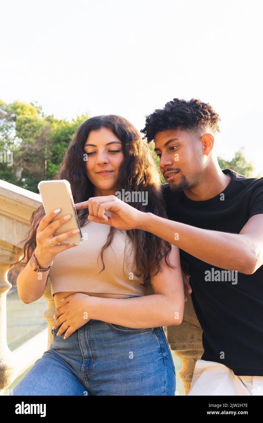 Young couple looking at smartphone while standing on steps in city Stock Photo