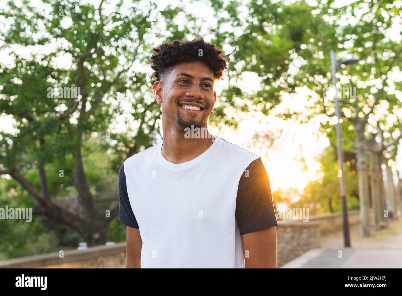 Cheerful young man looking away while standing at park Stock Photo