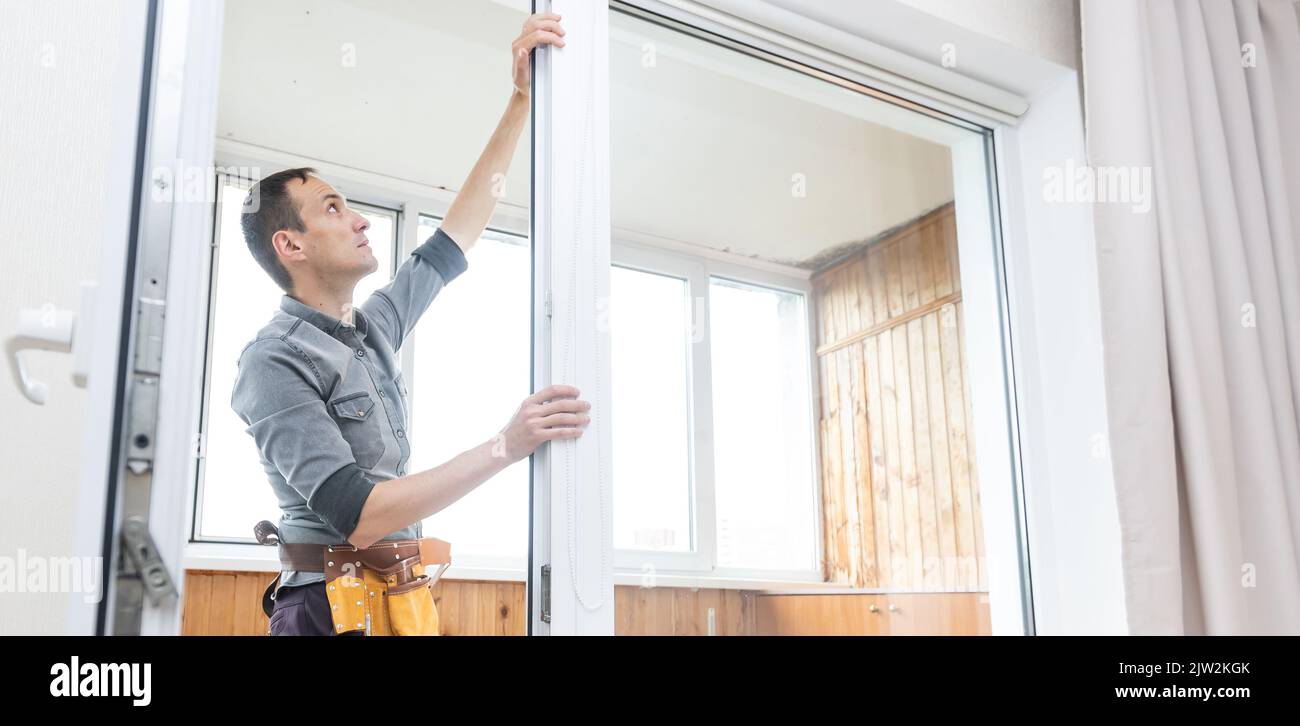 Construction worker removing sticky tape from window frame in house