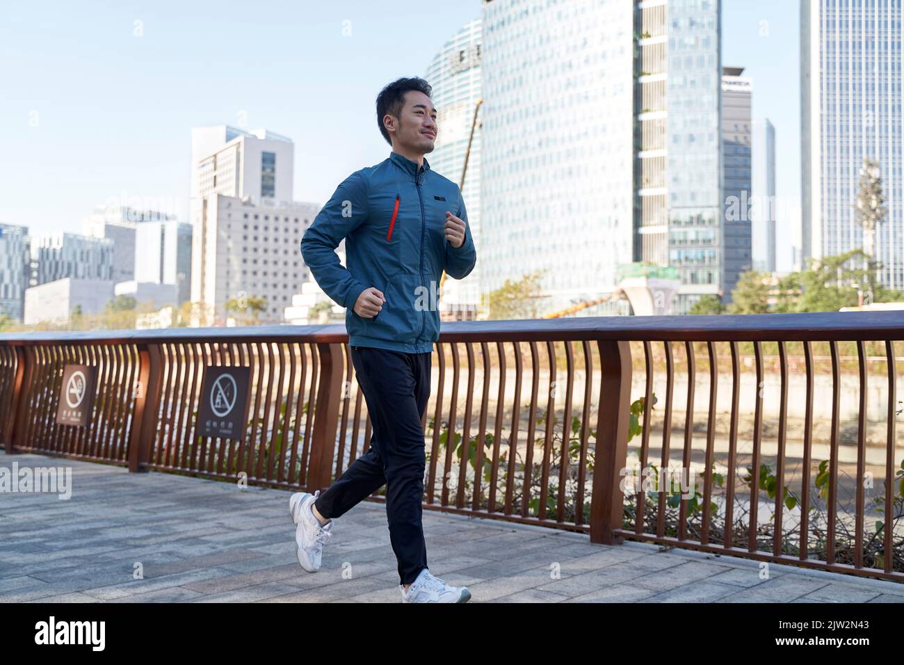 asian young adult man running jogging exercising in city park Stock Photo