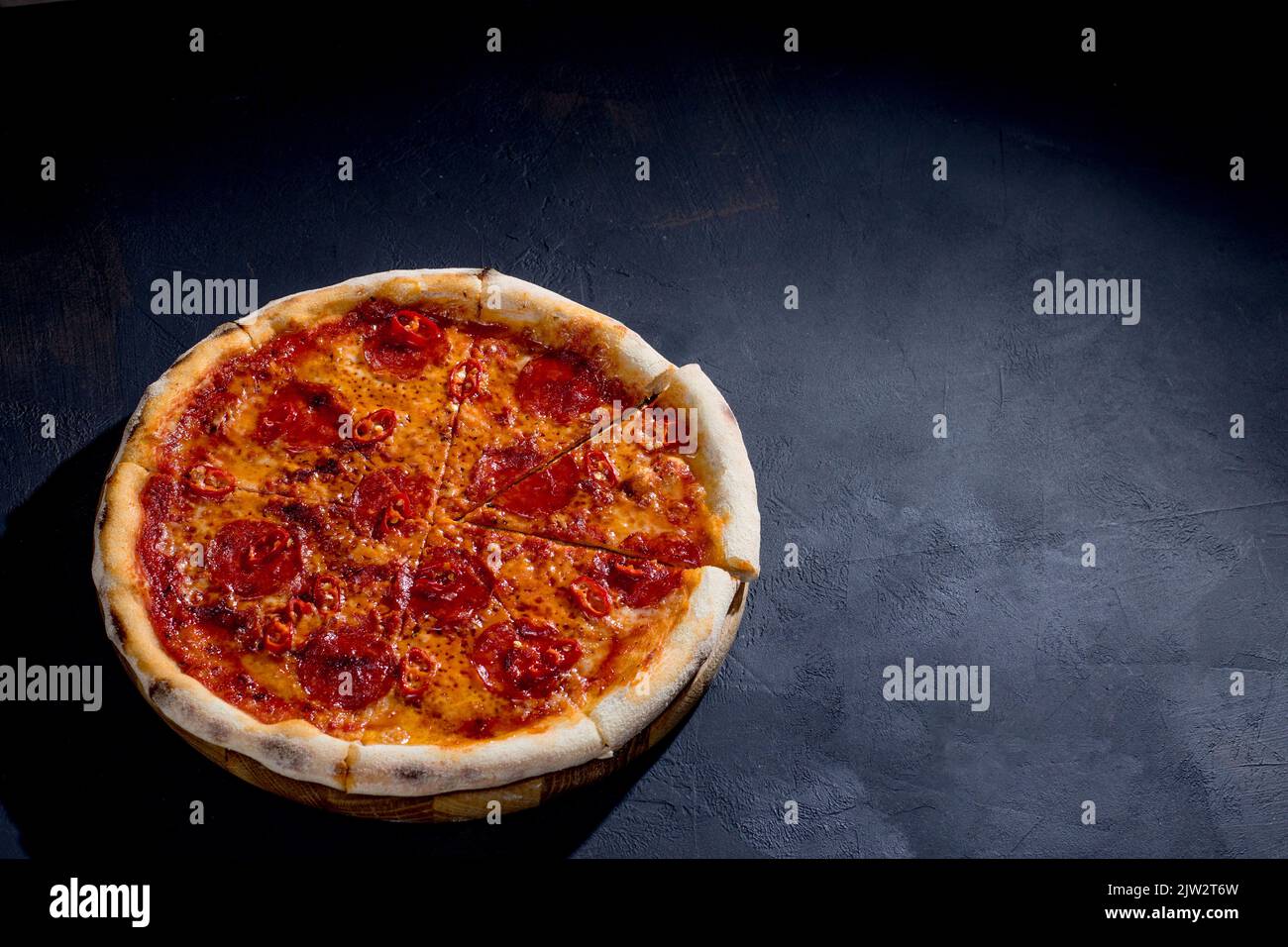 Pizza with tomato sauce, mozzarella, salami, chili, honey on black
