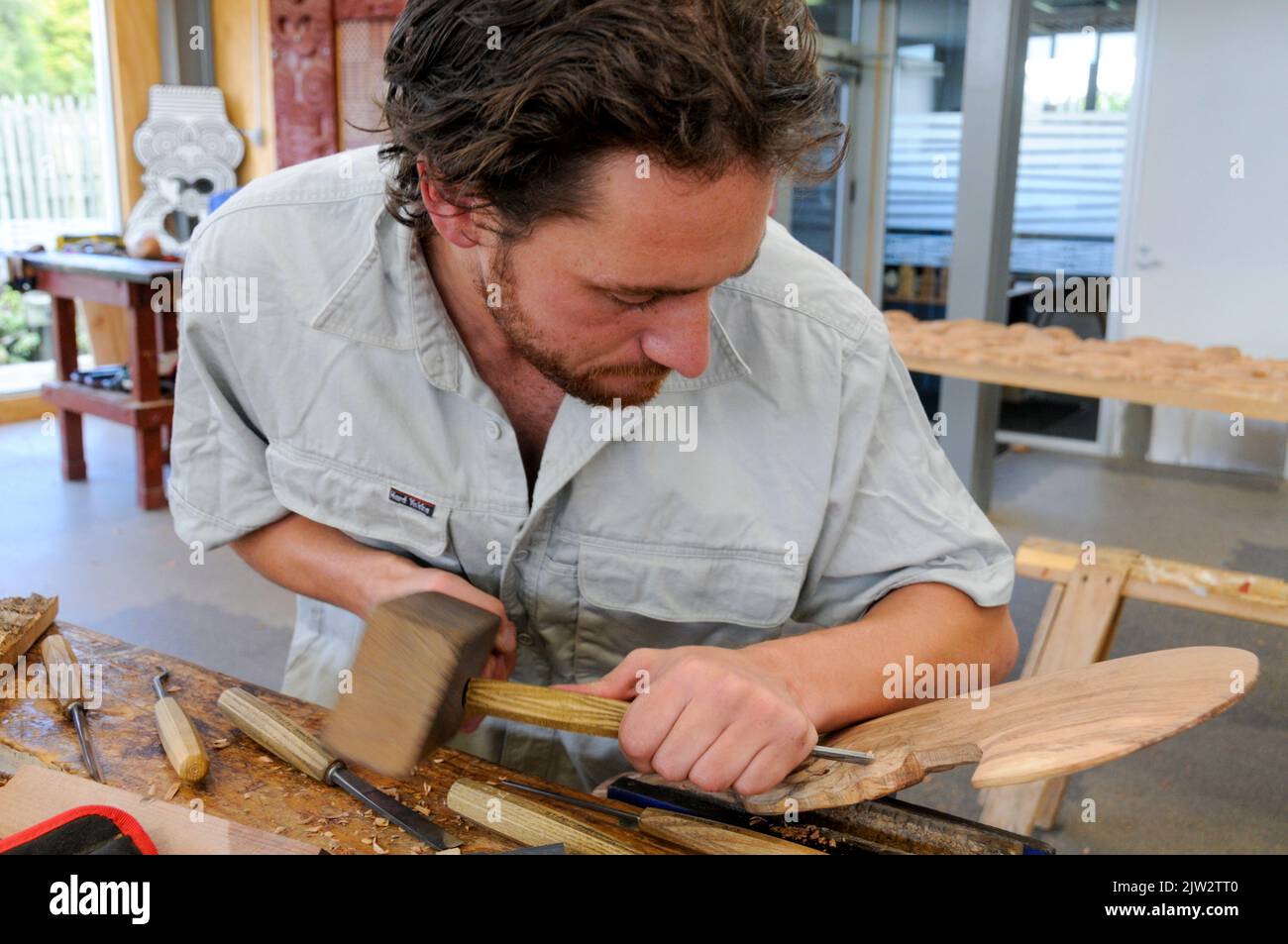 A wood carver is working on a Maori carving at the Carving school at Te Puia Maori arts and crafts Institute near Rotorua on North Island in New Zealand. Stock Photo