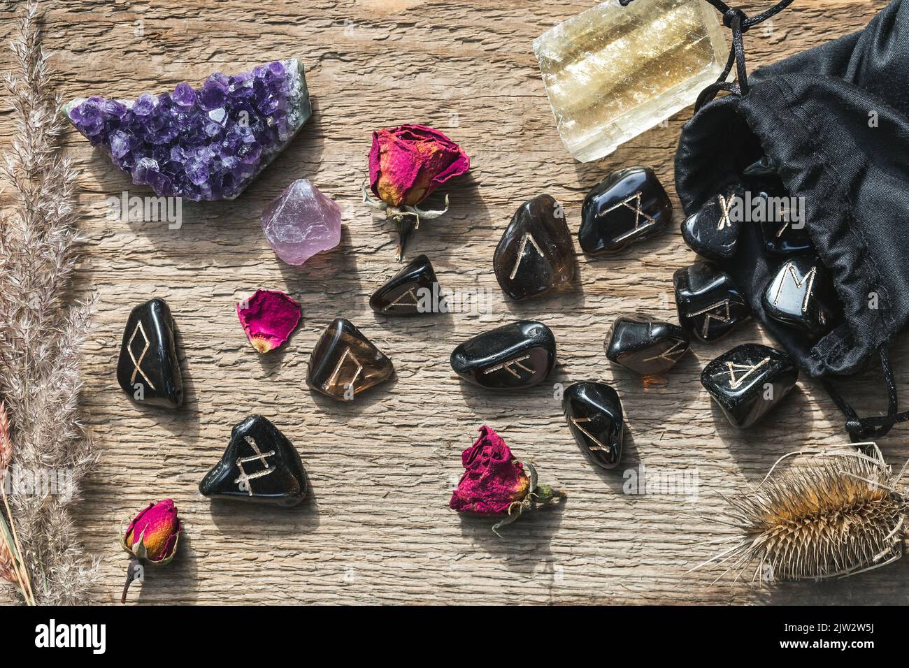 Set of different crystals and rune stones on wooden background. Amethyst cluster, fluorite, calcite, rose quartz, magical herbs and runes. Spiritual p Stock Photo