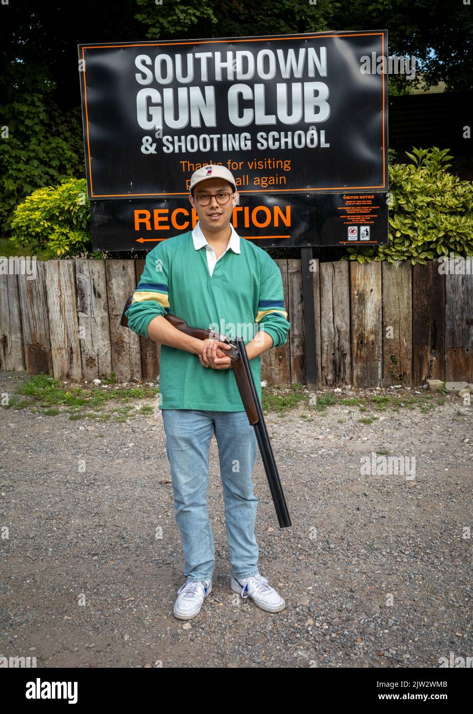 A young man stands with a 12-bore over and under shotgun at Southdown Gun Club & Shooting School at Findon, West Sussex, UK Stock Photo