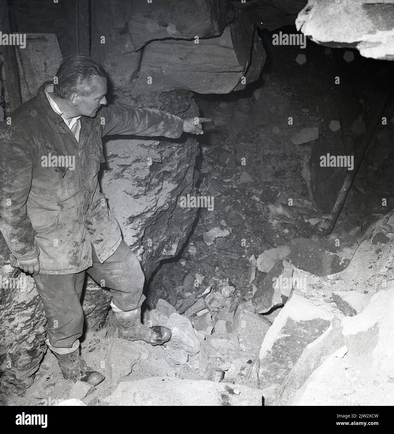 1960s, historical, a man pointing to the entrance of an abandoned, disused mine shaft, at the old coal mining village of Townshill, Fife, Scotland, UK. Stock Photo