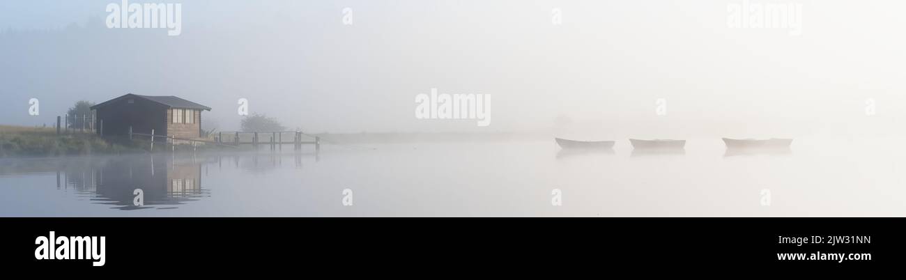 Fishing boats in lake and early morning mist at sunrise Stock Photo