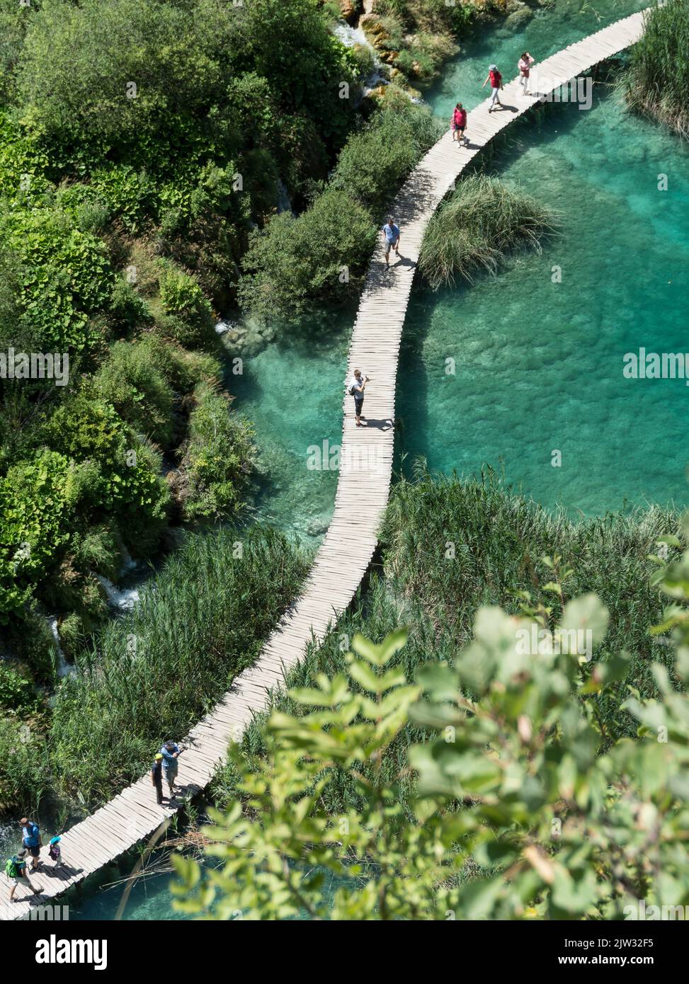 Aerial view of tourists walking on a board walk over one of the many pools and lakes of Plitvice Lakes National Park, Croatia, Europe. Stock Photo