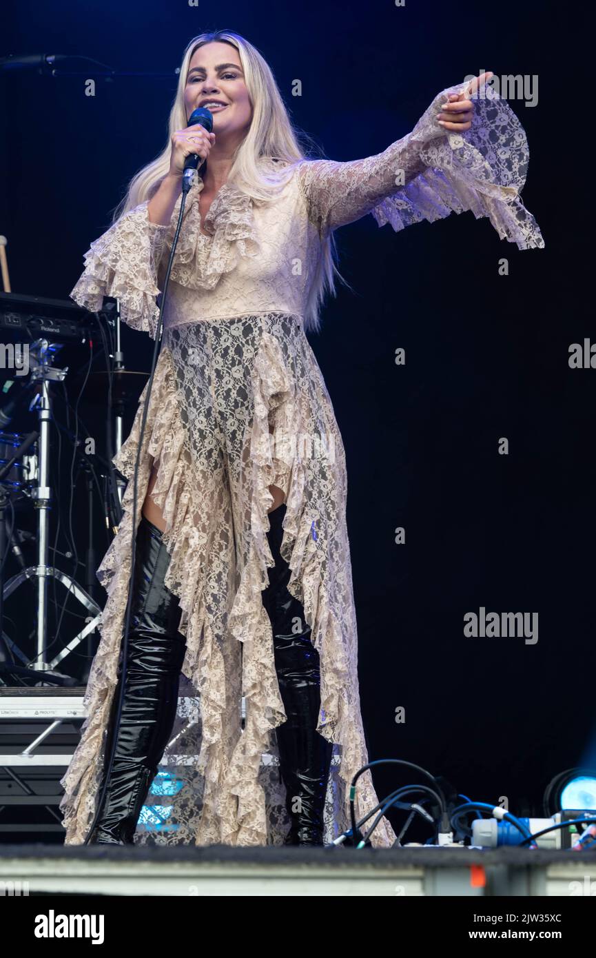 Lyra - singing to the connect audience wearing a lace thrilled blouse and black knee high boots Stock Photo