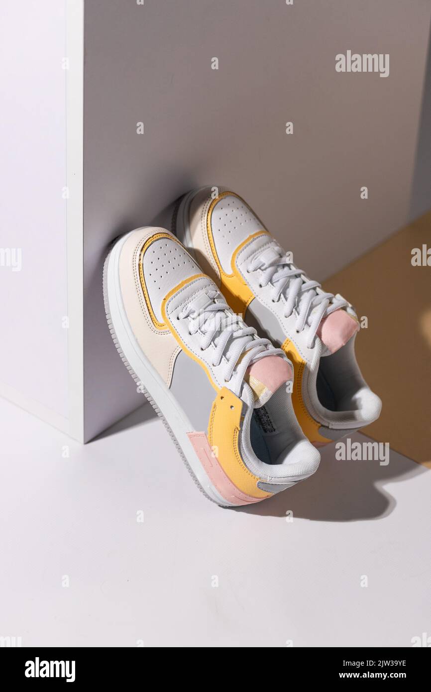 Close up of pair of colored sneakers standing leaning against white ...