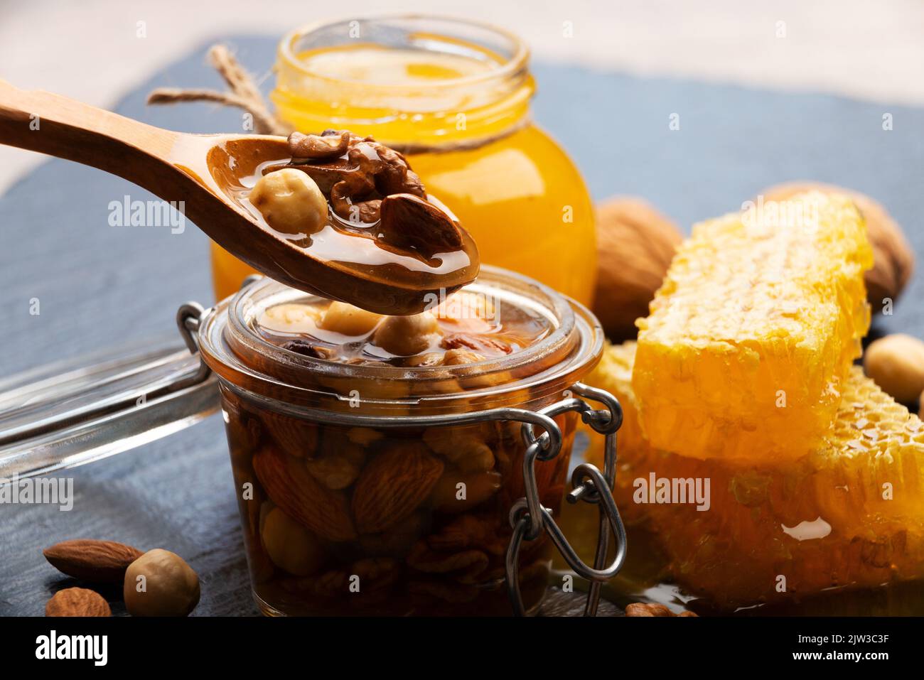 Honeyed assorted nuts in wooden spoon over mason jar organic food background Stock Photo