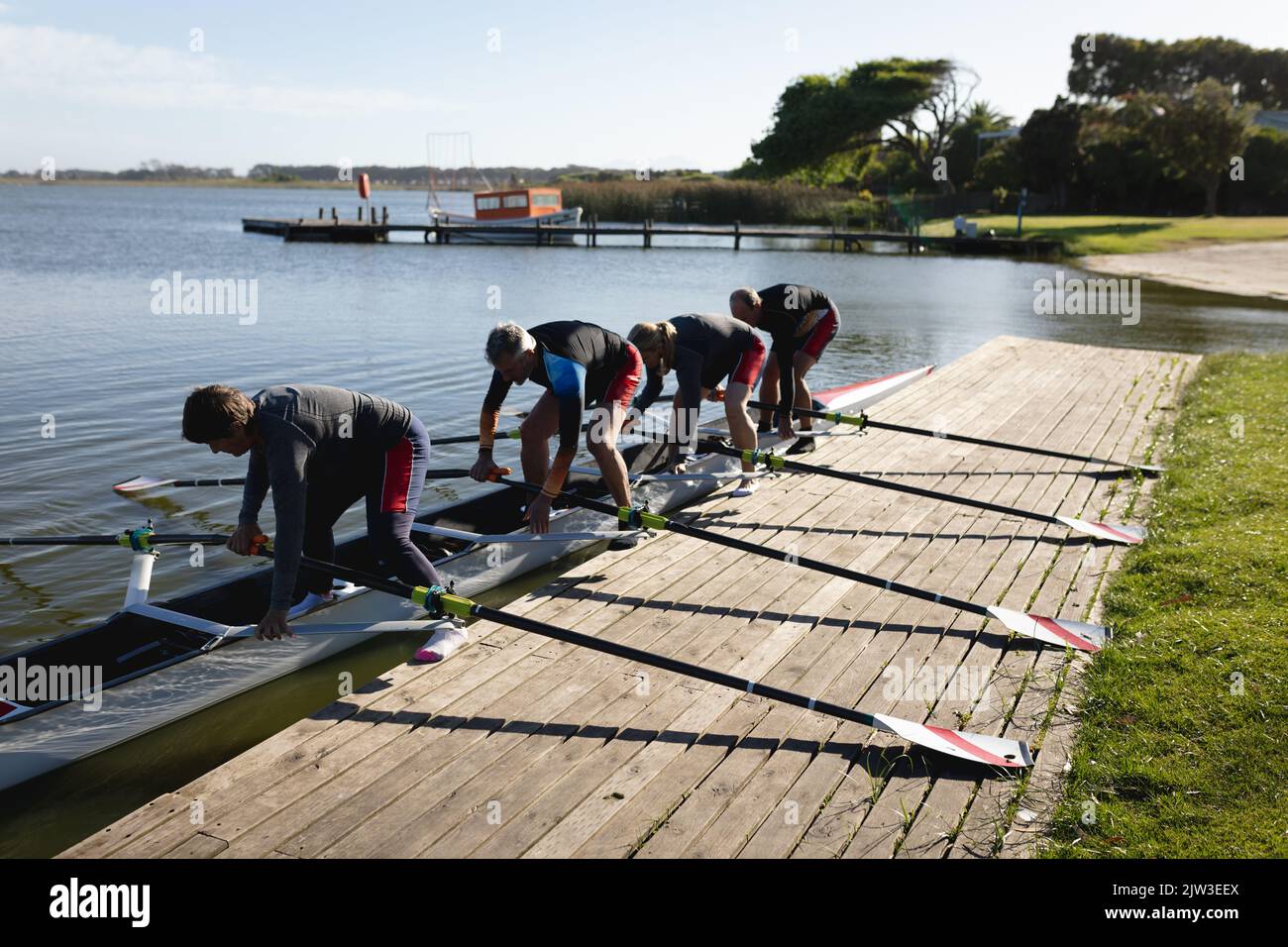 Senior caucasian rowing team attaching oars to the boat near the wooden