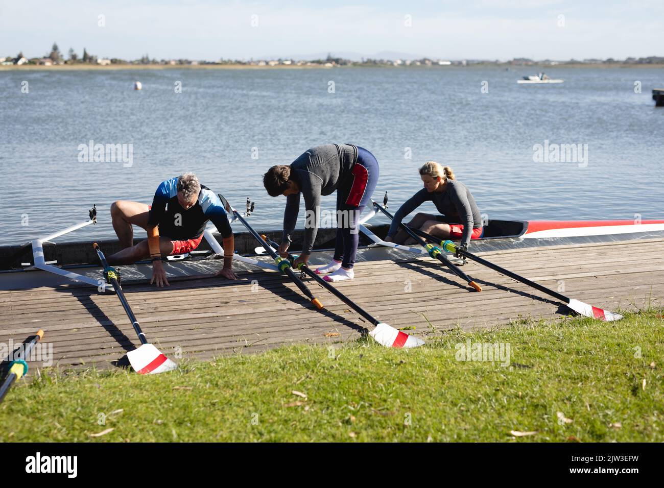 Senior caucasian rowing team attaching oars to the boat near the wooden