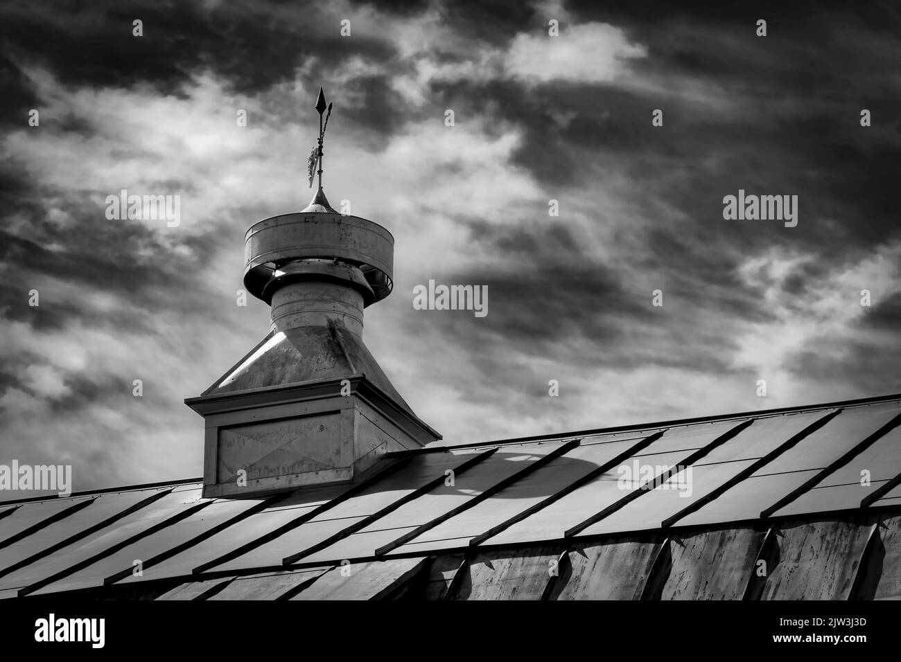 The blue sky behind the roof and weather vane of an old barn at Kossuth, an area near Manitowoc, Wisconsin. Stock Photo