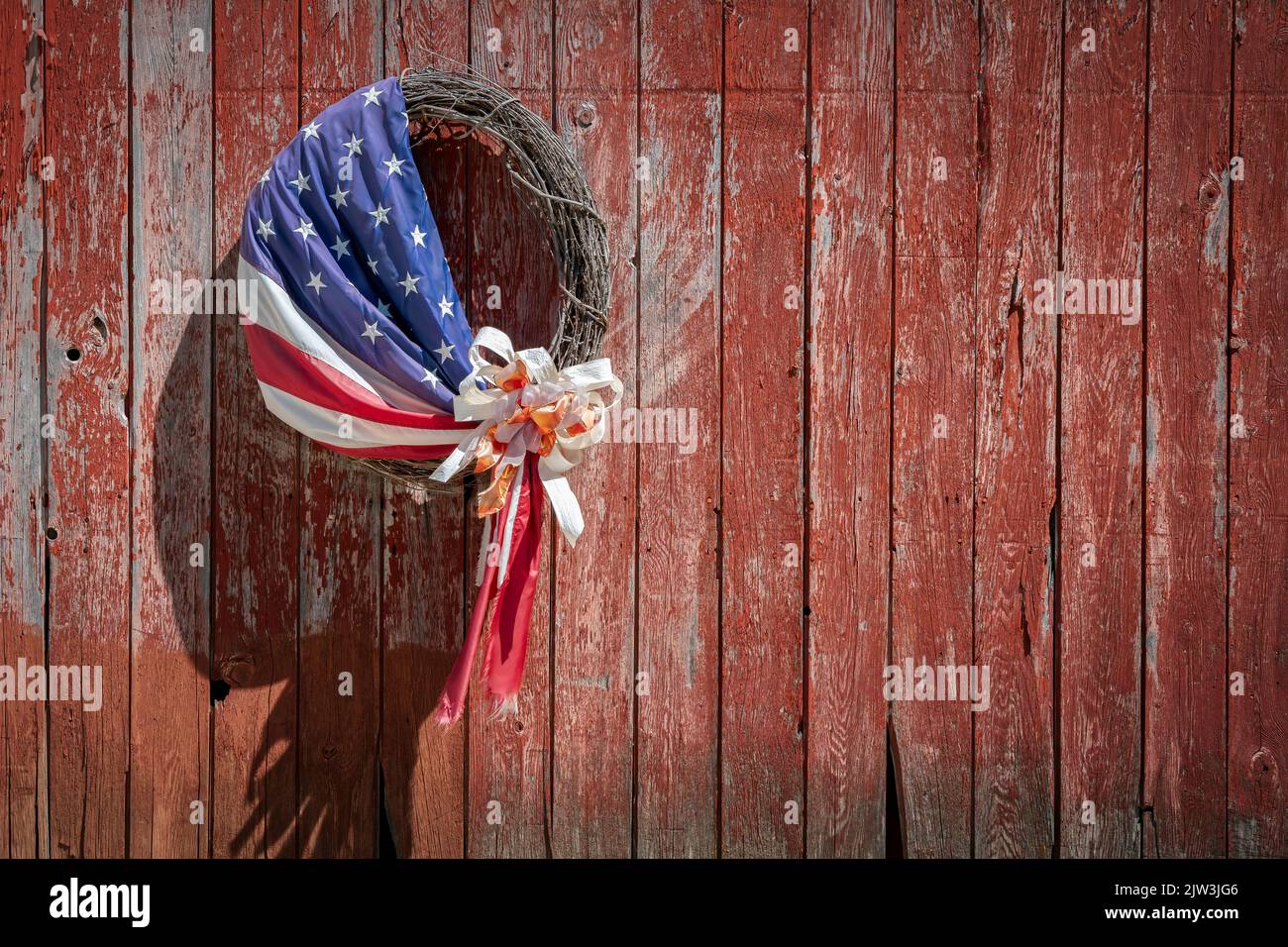 An American flag wrapped around a wreath made of sticks hangs on the side of a barn near Manitowoc, Wisconsin. Stock Photo