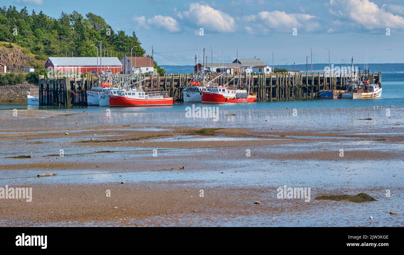Fishing boats moored at the wharf in Candy Cove Nova Scotia at low tide. Stock Photo