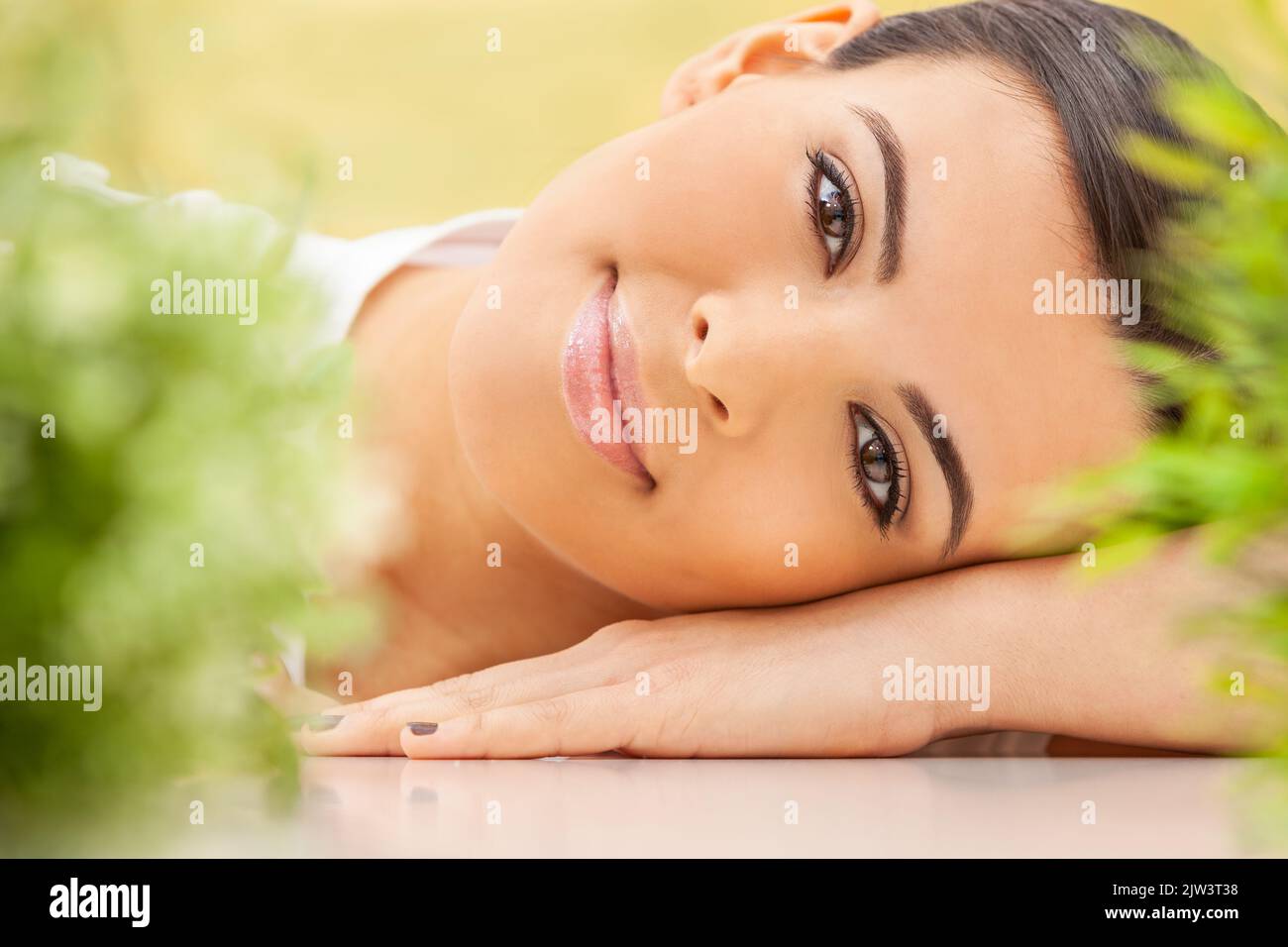 Health spa nature concept studio portrait of a beautiful young Hispanic Latina female young woman or girl resting on her hands smiling through natural Stock Photo