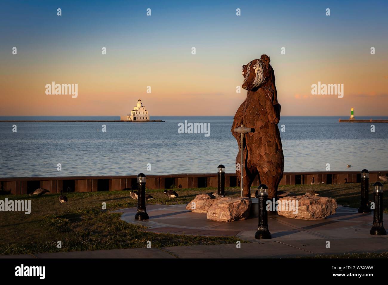 The sun sets on Shipbuilder, a 12-foot tall badger statue, created by sculpter Carl Vanderheyden standing at the harbor in Manitowoc, Wisconsin. Stock Photo