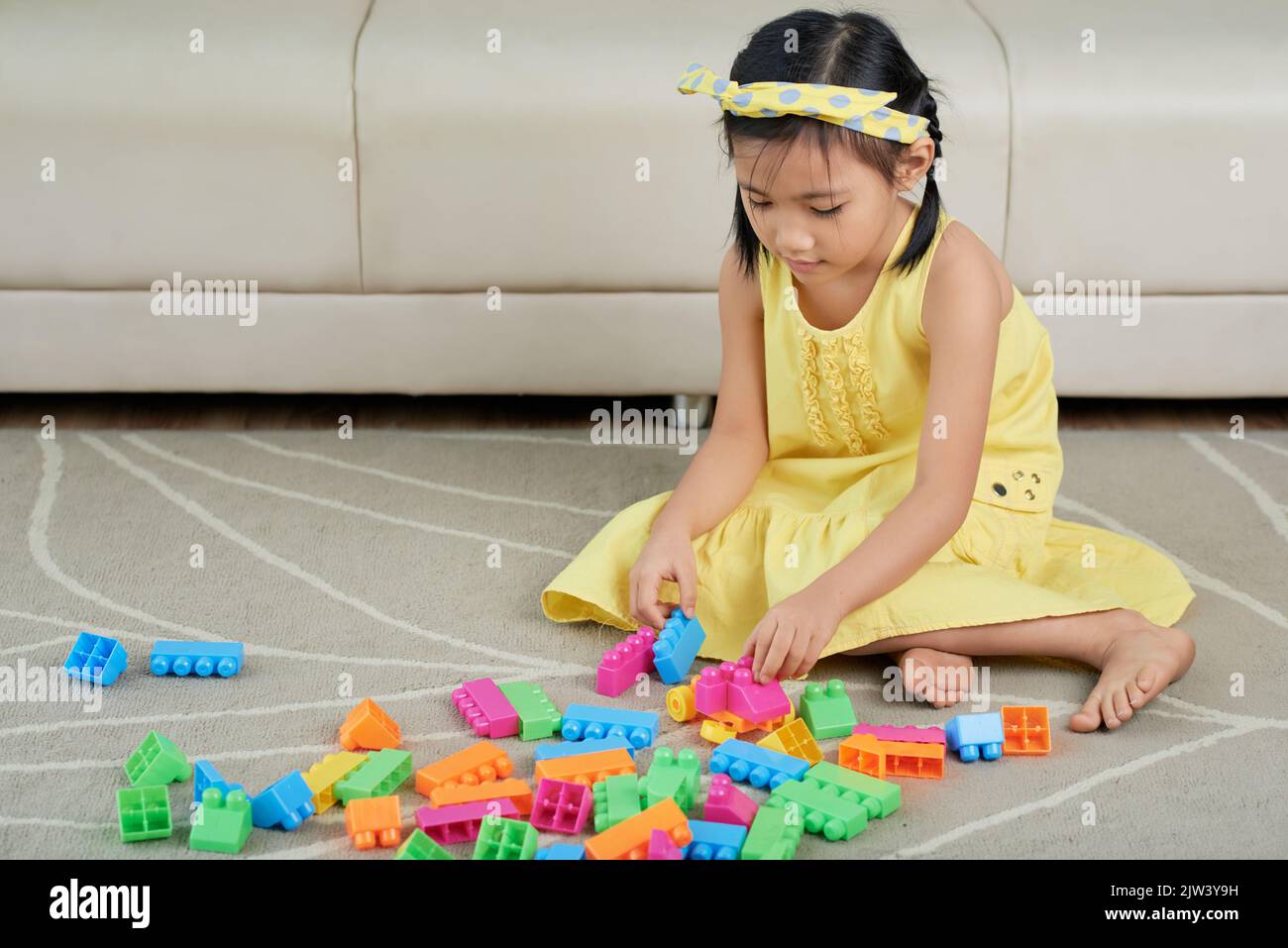 Little Asian girl playing on floor with her toys Stock Photo - Alamy