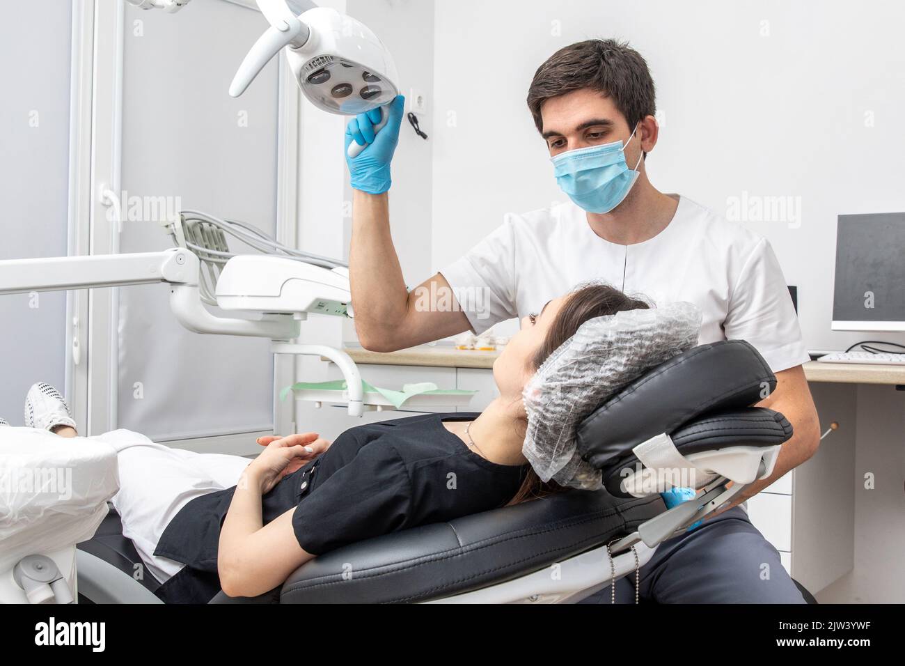 Dentist adjusting dental lamp in dental office. Dentist turning on lamp before treatment Stock Photo