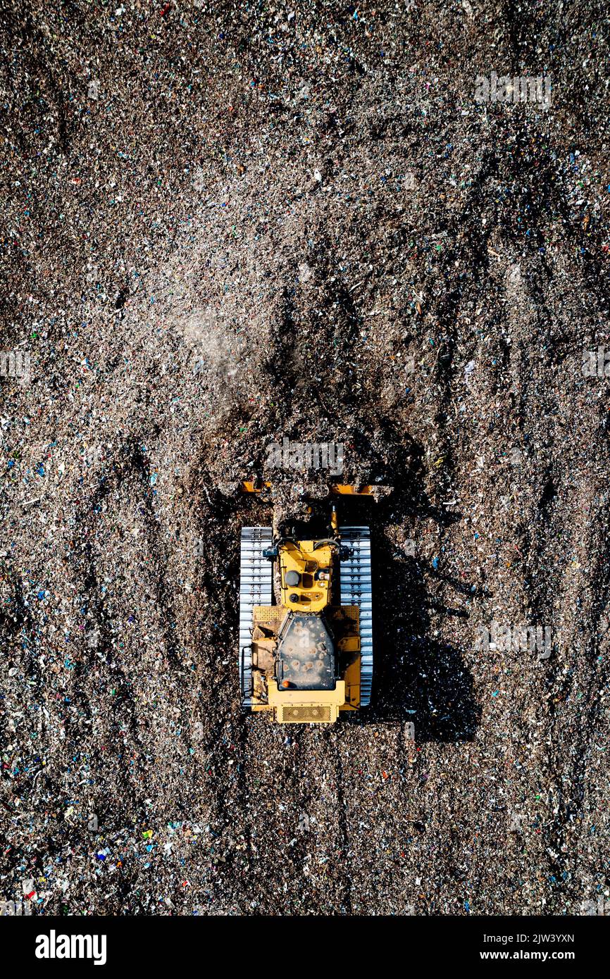 An aerial view of an industrial bulldozer moving household waste and gaebage on a large landfill site Stock Photo